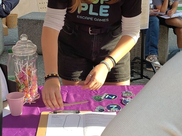 L’animatrice et le livret de jeu sur la table du stand.